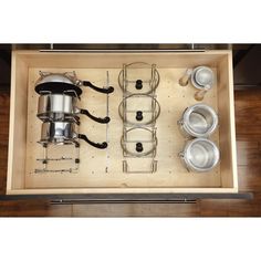 an overhead view of pots and pans in a wooden drawer with glasses on it