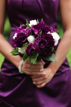 a woman holding a bouquet of purple and white flowers