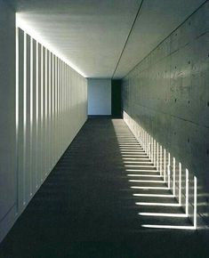 an empty hallway with long shadows on the wall