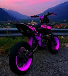 a purple and black dirt bike parked on the side of a road with mountains in the background