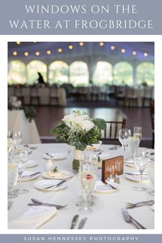 a table set up for a wedding reception with flowers in the center and windows on the water at frogbridge