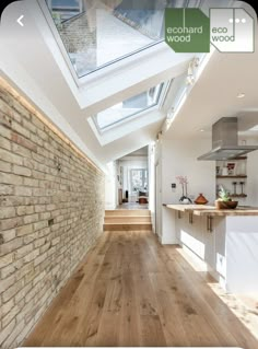 an open kitchen and living room with skylights on the ceiling, hardwood flooring