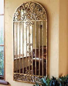 a mirror hanging on the side of a wall next to a potted plant in front of a window