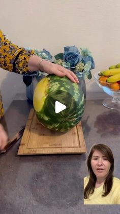 a woman cutting up a large watermelon on top of a table