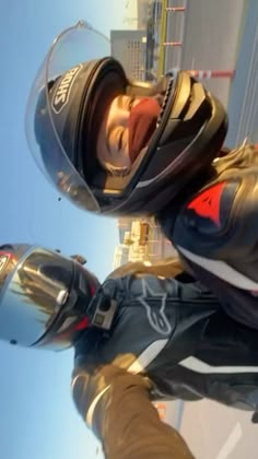 two people wearing helmets and standing next to each other in front of a tall building