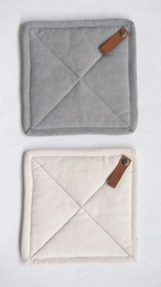 two pieces of cloth with leather tags attached to them, one in grey and the other in white