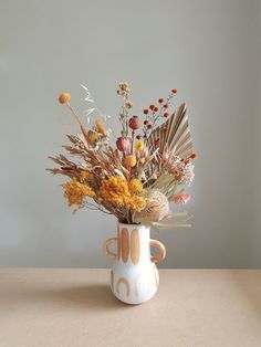 a white vase filled with lots of different types of flowers on top of a table