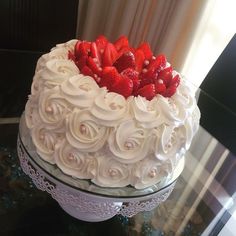 a cake with white frosting and strawberries on top is sitting on a table