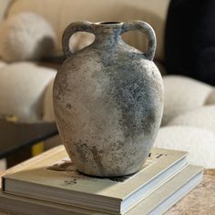 a gray vase sitting on top of a stack of books