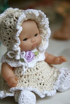 a small doll wearing a crocheted dress and bonnet