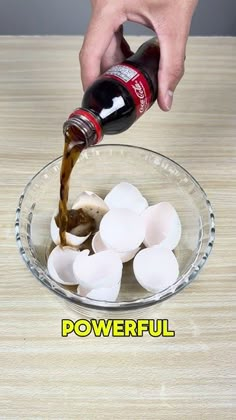 someone pouring beer into a glass bowl filled with ice cubes on top of a wooden table