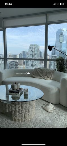 a living room filled with furniture and large windows overlooking the cityscape in the distance