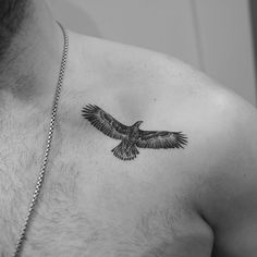 a black and white photo of a man's chest with a bird tattoo on it