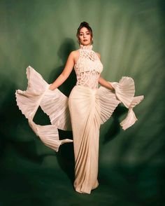 a woman in a white dress is posing with her hands on her hips and arms behind her back