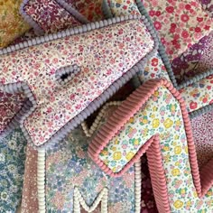 many different colored fabrics are laid out on top of each other, with the letter m in the middle