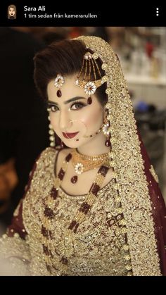 a woman wearing a gold and maroon bridal outfit