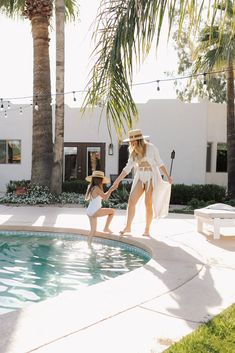 a mother and daughter playing by the pool in their backyard with palm trees behind them