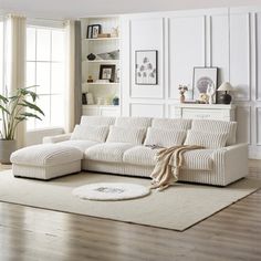 a living room with a white couch and rug on the wooden floor next to a large window