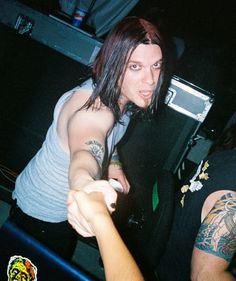 two people standing next to each other with tattoos on their arms and arm, one pointing at the camera