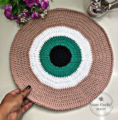 a crocheted placemat with a green center being held by a person's hand