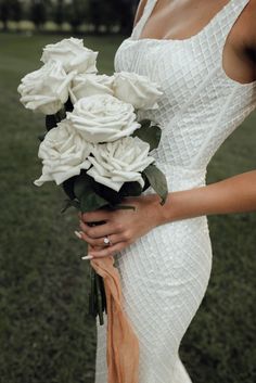 a woman holding a bouquet of white roses