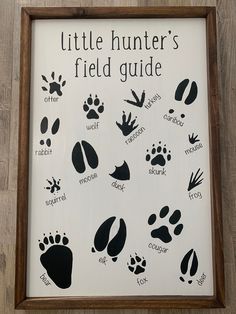 a wooden frame with black and white animal prints on it that says, little hunter's field guide