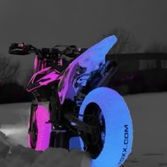 a pink and black dirt bike parked in the snow with its wheels turned upside down