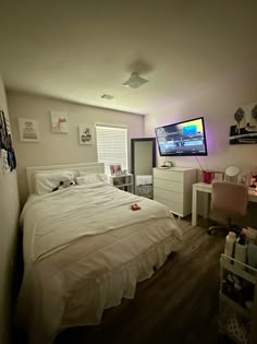 a bedroom with a bed, desk and television in it's corner next to a window