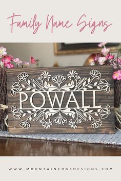 a wooden sign sitting on top of a table next to some pink flowers and branches