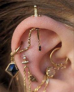 the ear is adorned with many different types of jewels and gold chain links, as well as an earring