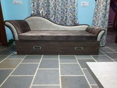 a couch sitting on top of a tiled floor next to a window with blue curtains