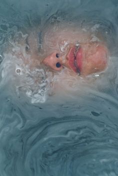 a woman is floating in the water with her head above the water's surface