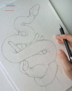 someone is drawing a snake on paper with a pencil