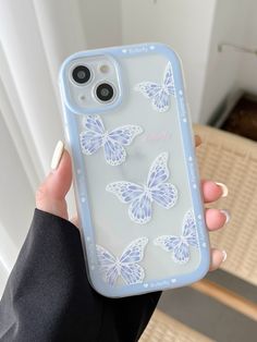 a woman is holding up her phone case with butterfly decals on the front and back