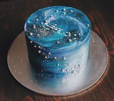 a blue and white cake sitting on top of a metal plate with sprinkles