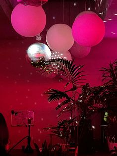 pink and white lights hanging from the ceiling in a room filled with potted plants