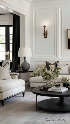 a living room filled with white furniture and black accents on the walls, along with a round coffee table