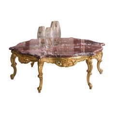 a marble topped coffee table with two wine glasses on it's top and gold legs