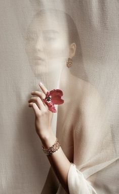 a woman is holding a flower in her right hand and wearing jewelry on her left arm