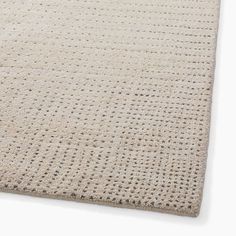 the textured rug is beige and has black dots on it, as well as a white background