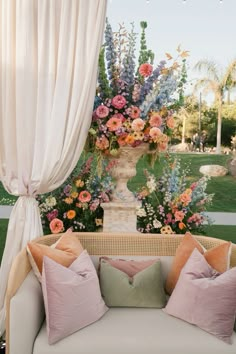 a white couch sitting in front of a lush green field filled with lots of flowers