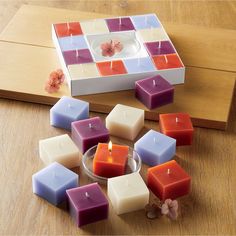 several different colored candles sitting on top of a wooden table