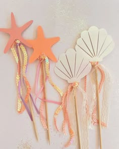 three little mermaid wands with starfish, seashell and shell decorations on them