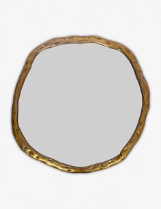 an oval shaped mirror made out of wood and gold leafy branches, on a white background