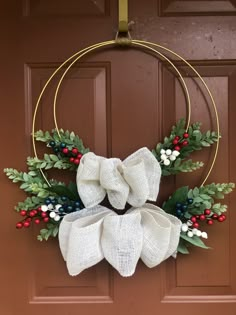 a wreath with white bows and berries hanging on a door