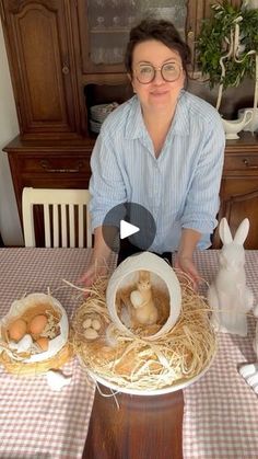 a woman sitting at a table in front of some fake eggs and rabbits on top of it