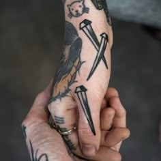 a person holding their hand with tattoos on it's fingers and two crossed swords in the middle