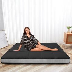 a woman sitting on top of a black mattress