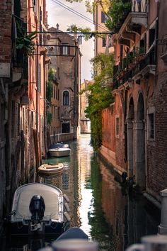 boats are parked on the side of a narrow canal in venice, italy with buildings lining both sides