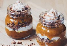 two jars filled with dessert sitting on top of a wooden table